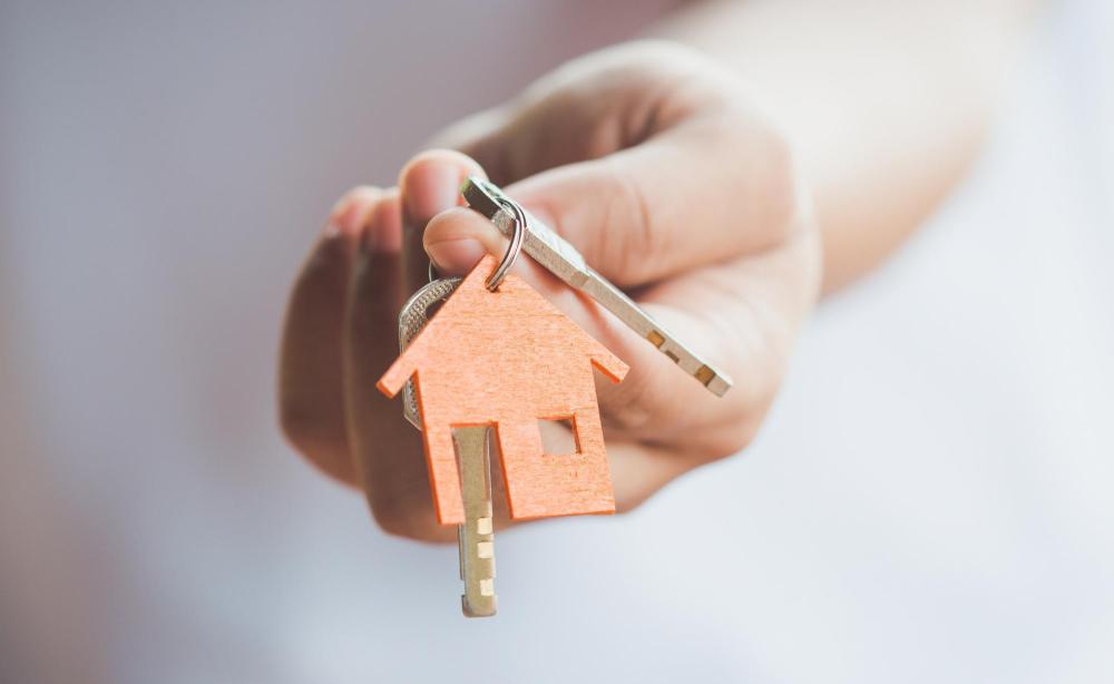 Main qui tient une maison et une clé